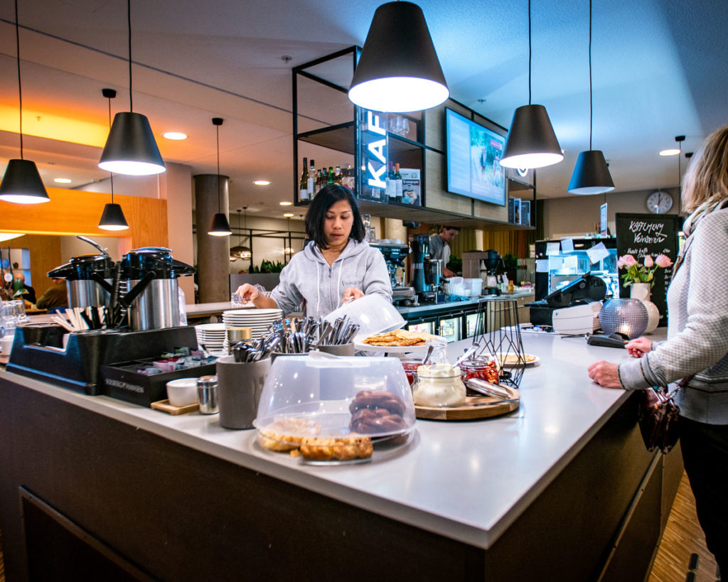 Bilde fra kafé Veiviseren på Lørenskog hus. Barista som betjener kunde.