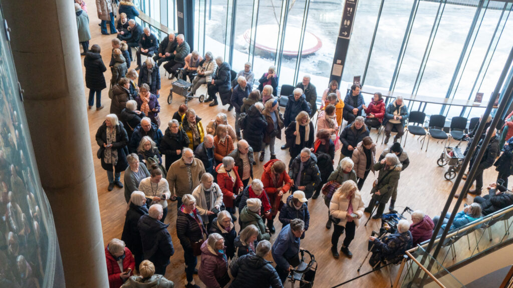 En sto gruppe eldre folk i en foajé.